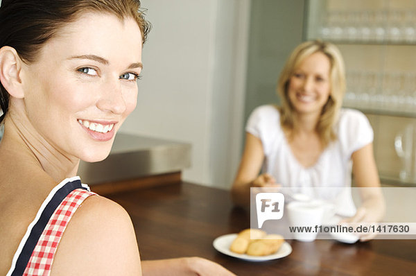 2 lächelnde Frauen am Tisch sitzend