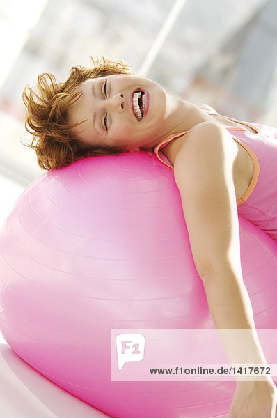 Junge lächelnde Frau lehnt sich an einen großen rosa Ballon.