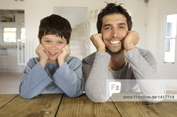 Vater und Sohn lächeln für die Kamera  mit Händen auf den Wangen.