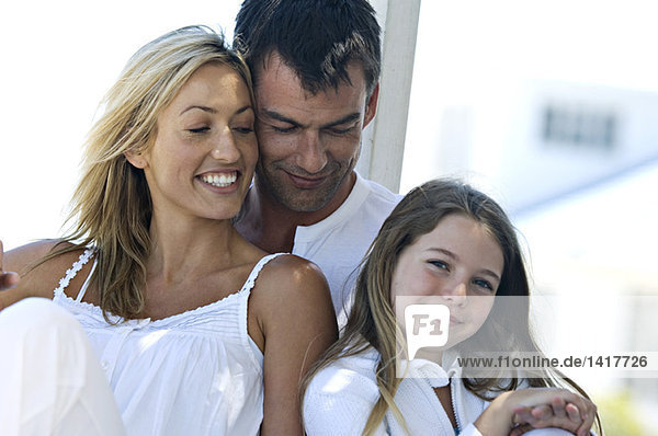 Eltern und Tochter lächeln für die Kamera  im Freien