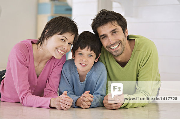 Parents and son smiling for the camera  lying on floor