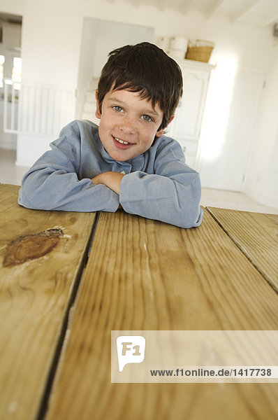 Kleiner Junge lächelt für die Kamera  auf dem Tisch liegend