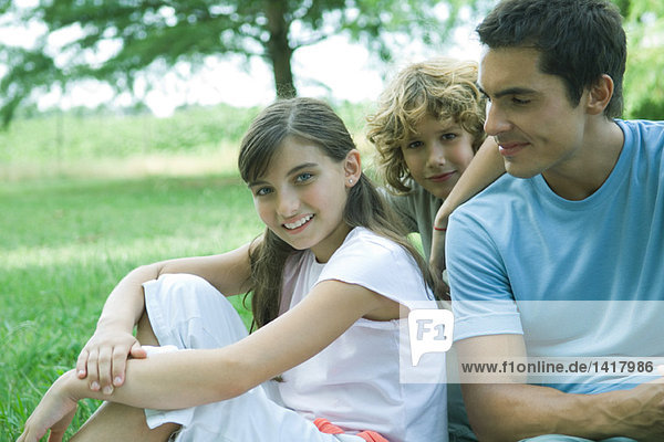 Mann sitzend im Freien mit Sohn und Tochter