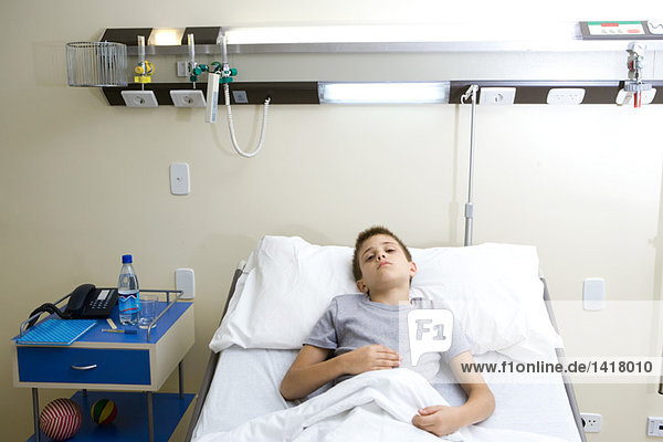 Junge im Krankenhausbett liegend  den Bauch haltend