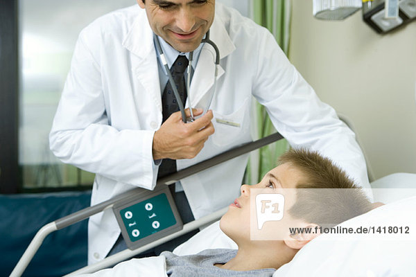 Arzt im Gespräch mit dem im Krankenhausbett liegenden Jungen