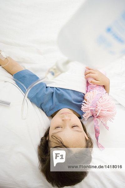 Mädchen im Krankenhausbett liegend  Puppe haltend