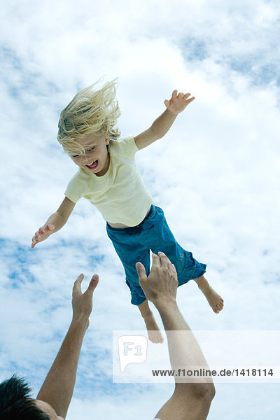 Man throwing little girl into the air  low angle view