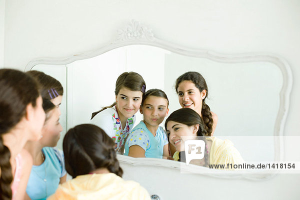 Vier junge Freundinnen schauen gemeinsam in den Spiegel