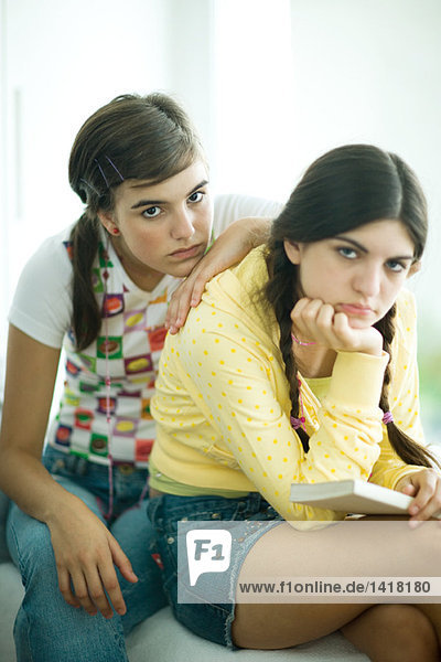 Two young female friends slouching and looking bored  looking at camera  portrait