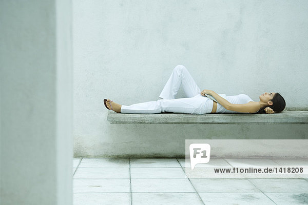 Woman lying on bench  full length  side view
