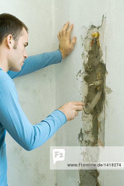 Mann füllt das Loch in der Wand mit Mörtel aus.