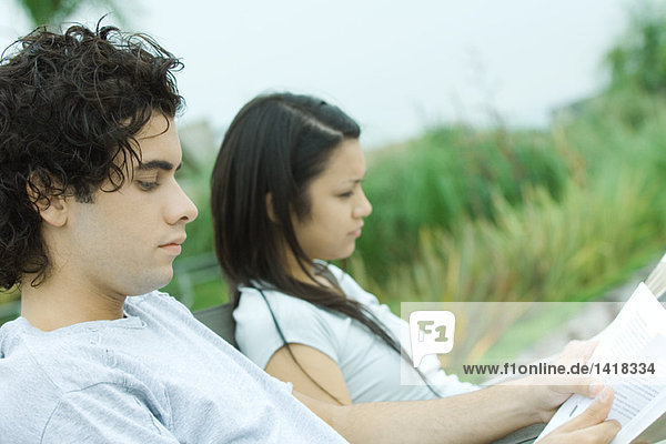 Junges Paar beim Lesen im Freien