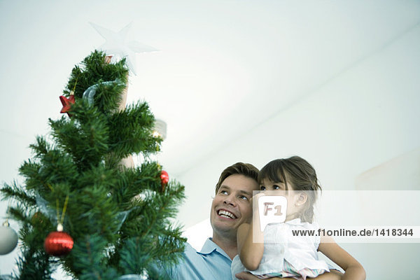 Vater und Tochter platzieren Stern auf dem Weihnachtsbaum
