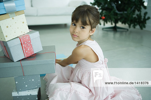 Mädchen sitzend neben einem Stapel von Geschenken