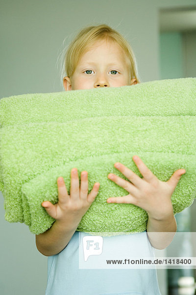 Mädchen hält einen Stapel gefalteter Handtücher.