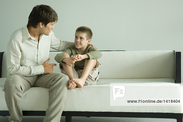 Father and son sitting on sofa  talking