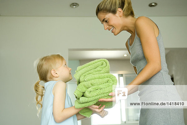 Mutter und Tochter  Mädchen  das der Frau Handtücher überreicht