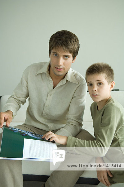 Vater und Sohn schauen aus der Zeitschrift auf.