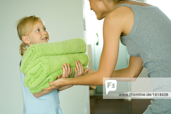 Mädchen  die ihre Mutter mit gefalteten Handtüchern ausstattet.