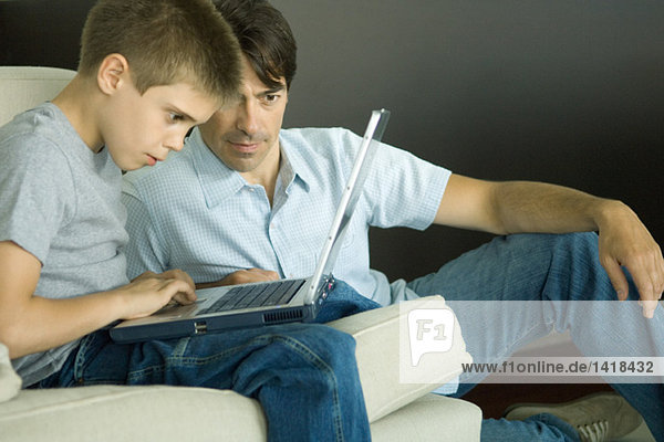 Vater und Sohn nutzen gemeinsam den Laptop