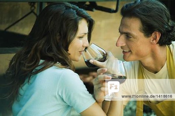 Paar trinkt Rotwein mit verbundenen Armen