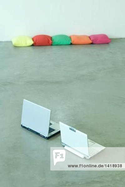 Zwei Laptops auf dem Boden  Kissen im Hintergrund