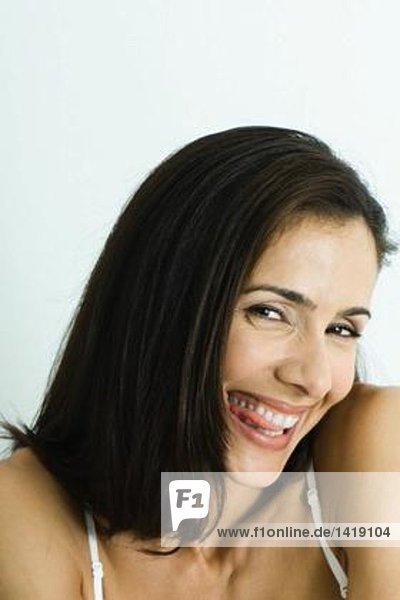 Frau beißt Zunge  lächelt in die Kamera  Portrait