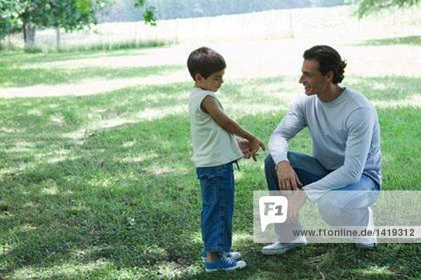 Junge und Vater reden im Freien