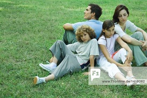 Familie im Freien  sitzend auf Gras Rücken an Rücken