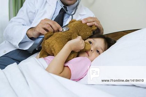 Arzt hält Stethoskop an Teddybär eines kranken Kindes