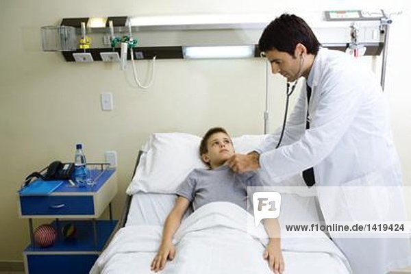 Kind im Krankenhausbett liegend  Arzt neben dem Bett stehend