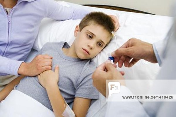 Boy having IV drip adjusted in hospital