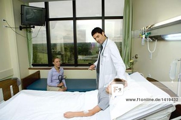 Child lying in hospital bed  doctor standing by side