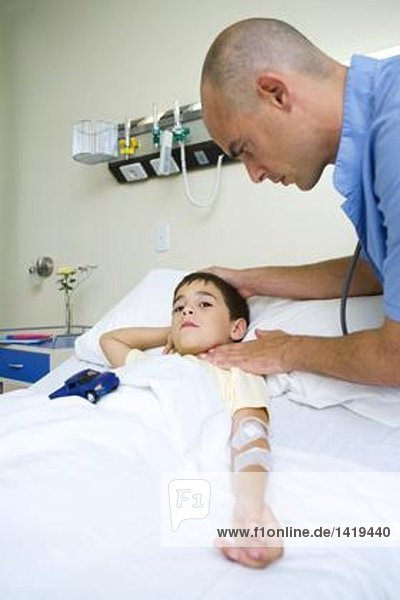 Junge im Krankenhausbett liegend  Arzt am Puls der Zeit