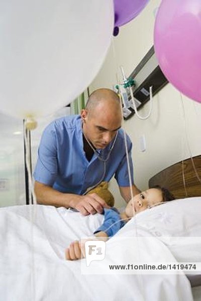 Mädchen im Krankenhausbett liegend  umgeben von Luftballons