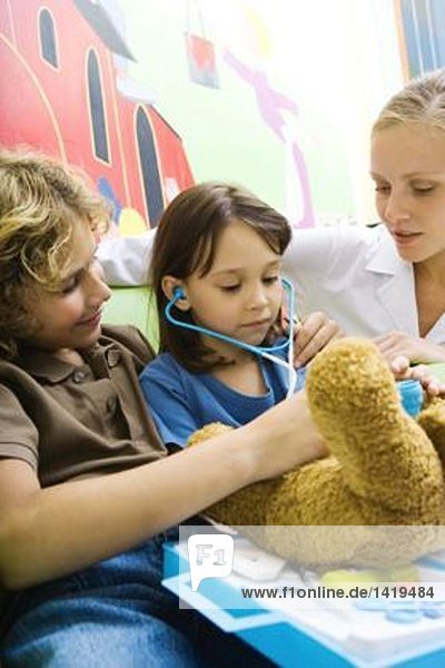 Junge und Mädchen spielen Doktor mit Teddybär