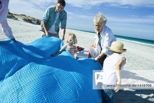 Familie am Strand  Decke ausbreiten