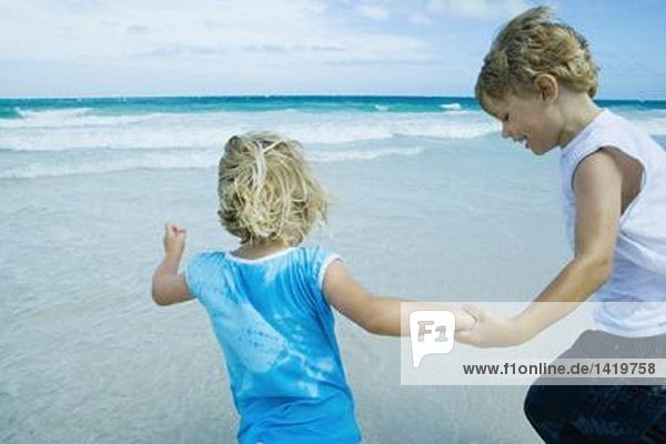 Kinder halten sich am Strand an den Händen