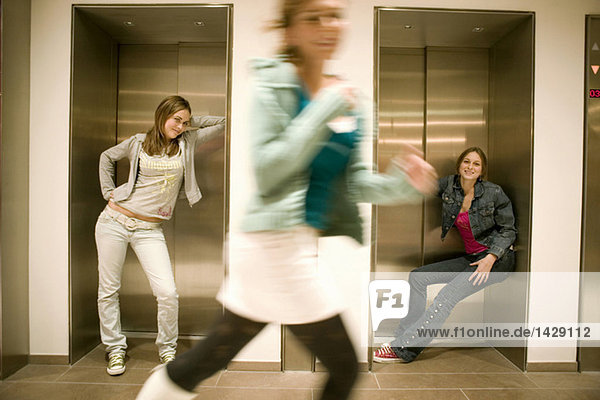 Zwei Frauen  die sich an die Aufzugstür lehnen  eine Frau  die läuft.