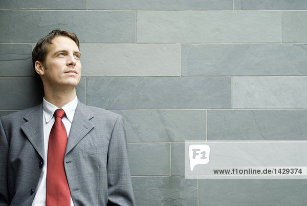 Businessman leaning against wall