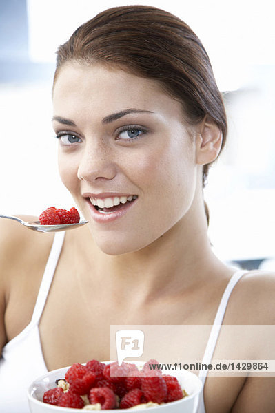 Young woman holding bowl with rasberries