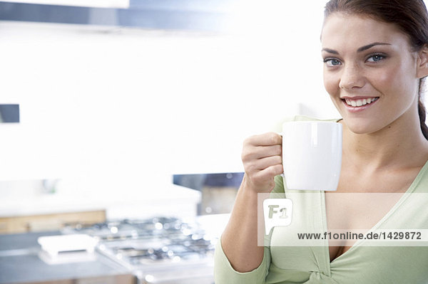 Young woman in kitchen  holding cup