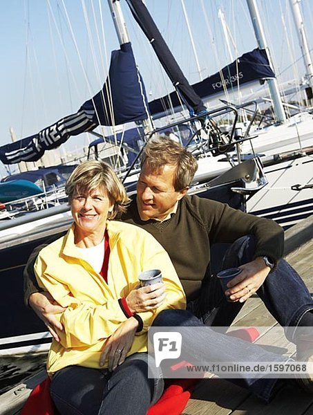 Porträt eines mittleren Alters Paares sitzen in einem Hafen.
