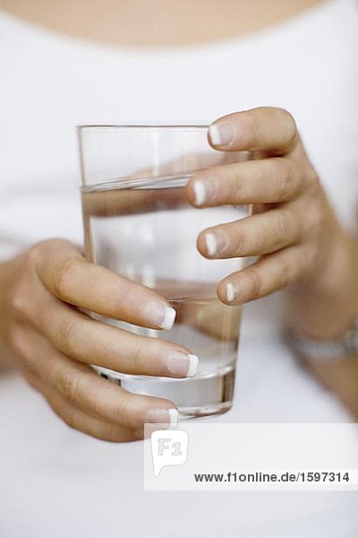 Ein Glas Wasser in den Händen einer Frau.