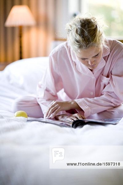 Eine Frau sitzen in einem Bett lesen ein Papier.