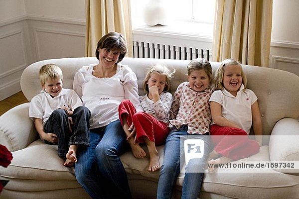 Mother and children sitting in a sofa.