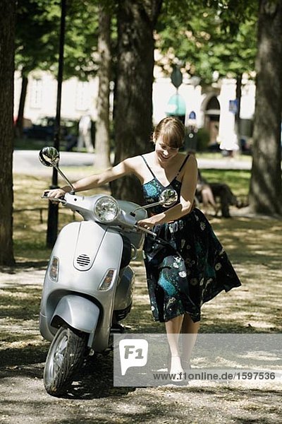 Young Scandinavian woman and a motor scooter Sweden.