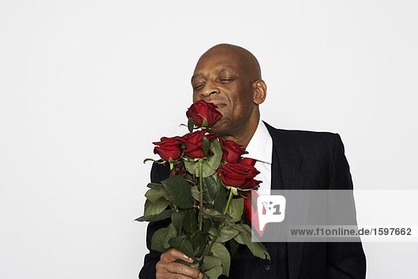 Ein Mann in einem Anzug halten ein paar rote Rosen.