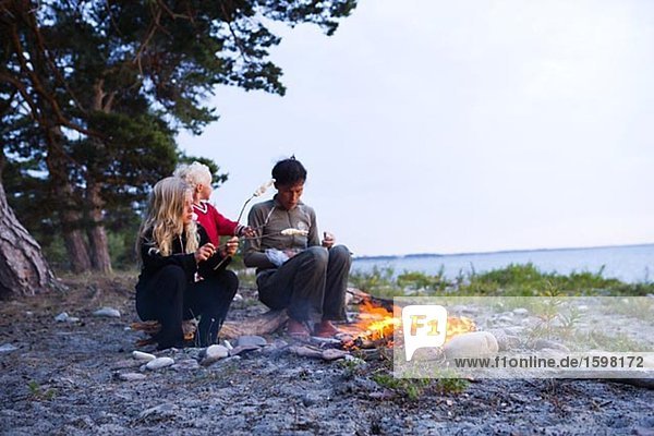 Eine skandinavische Frau und zwei Mädchen sitzen von einem Lager Feuer Oland Schweden.