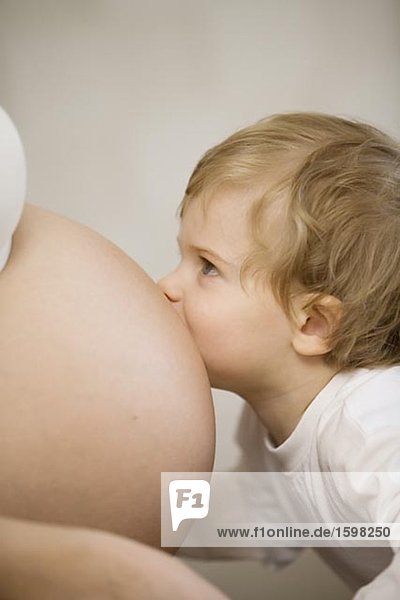 A little child kissing the stomach of a its pregnant mother Sweden.